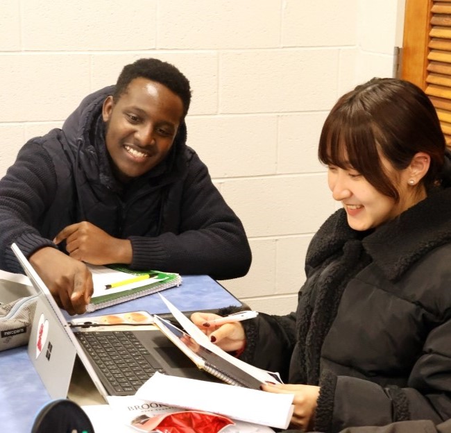 image of two students seated together and working with a computer in front of them