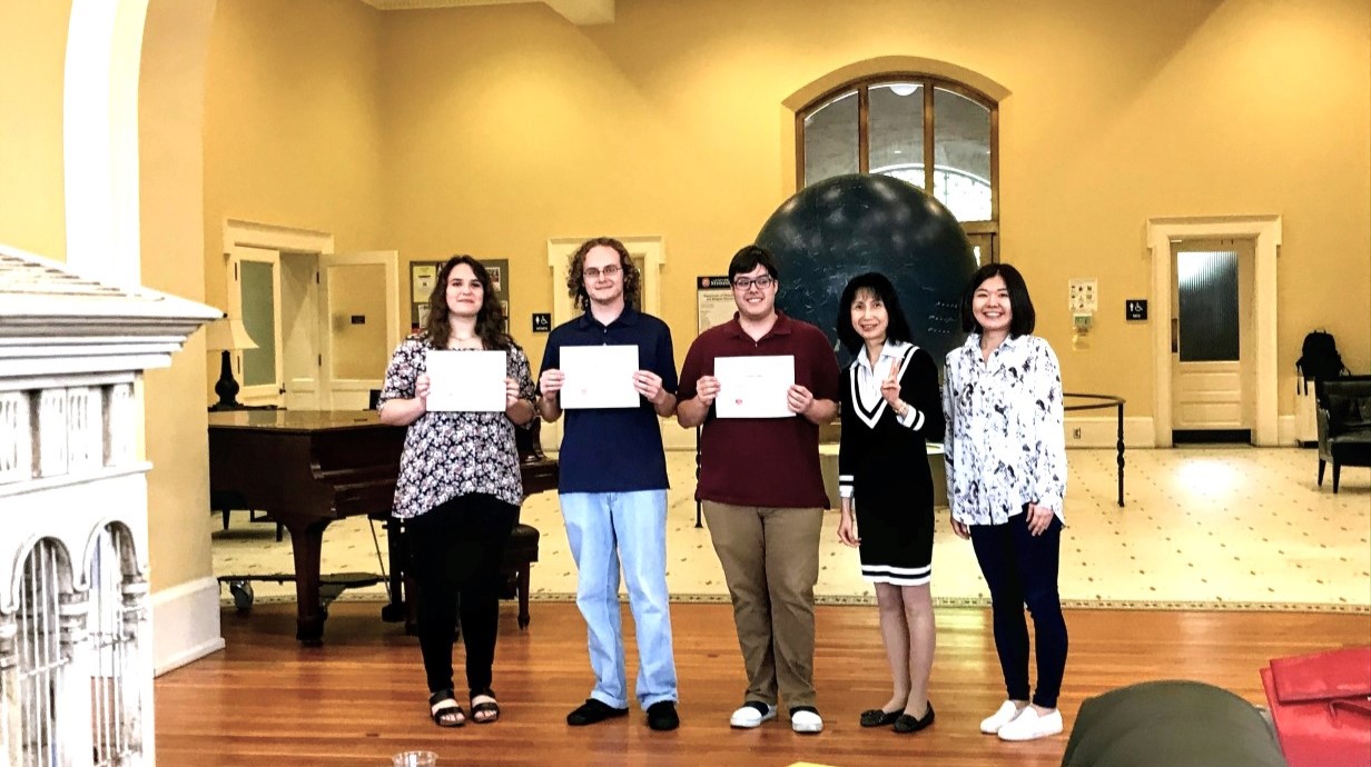 image of a few award winning students holding certificates and standing with professor