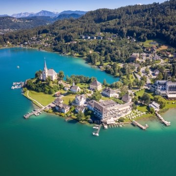 aerial view of an Austrian town on a peninsula on a lake with forests and mountains