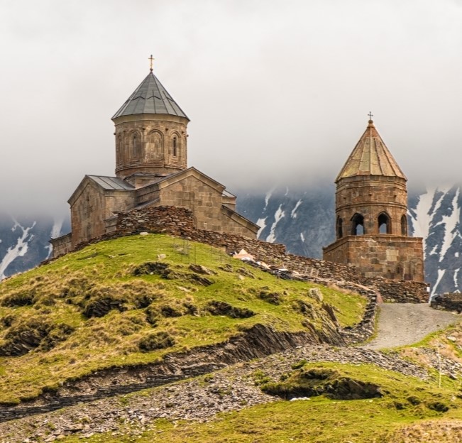 image of old churches on top of hills with mountains and fog in the background.