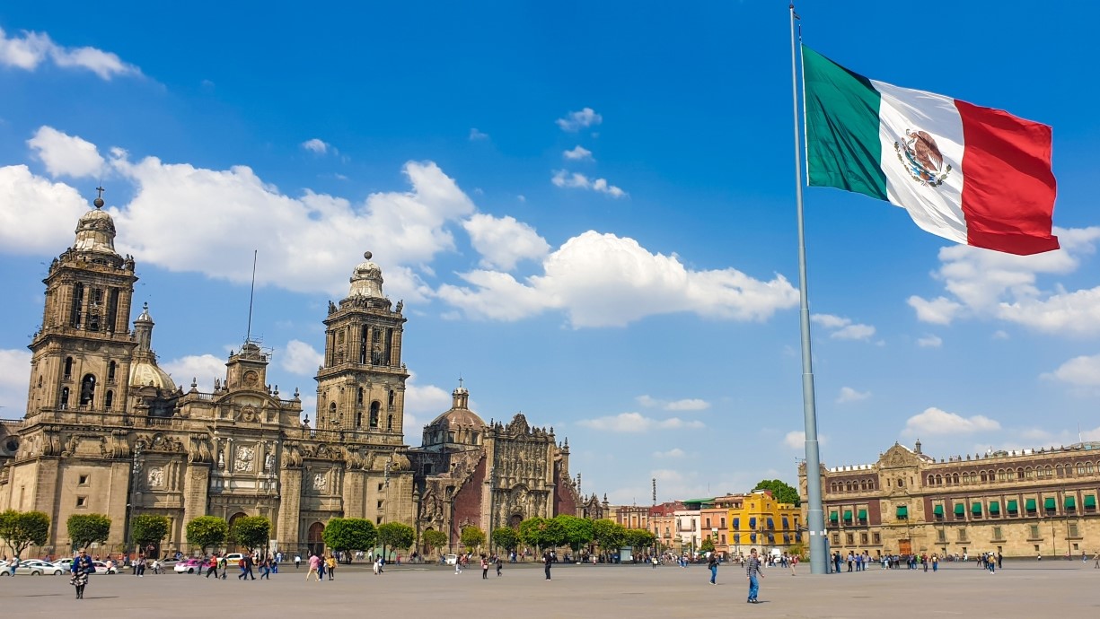 image of the main square in Mexico CIty with a large cathedral, Mexican flag, and presidential palace