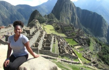 student seated with archaeological ruins and mountains of Machu Picchu 