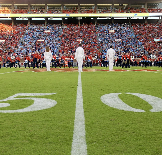 3 Pride of the South members in the stands at Vaught Hemingway smile and laugh at the camera, one holds up a "peace sign"