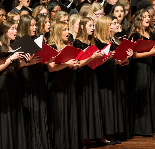 Ole Miss choir in black dress singing with red choir books