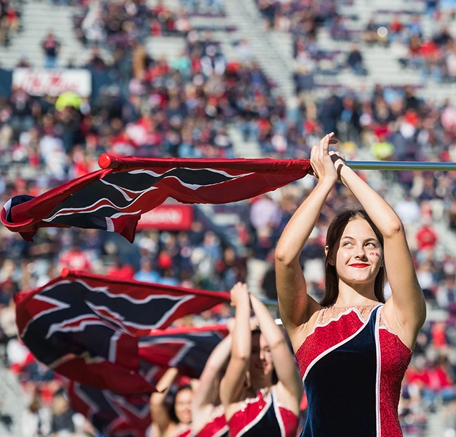 A color guard member smiles and spins her flag during a halftime performance