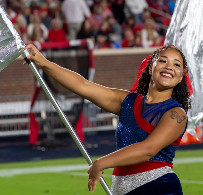 A color guard member smiles and spins her flag during a halftime performance