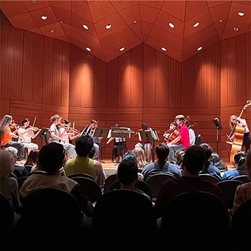 small group of students on stage playing string instruments