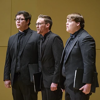 Three members of the Men's Glee perform in a trio during a concert