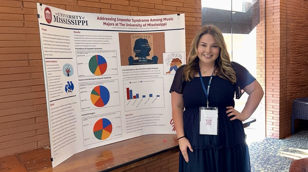 A music education grad student stands in front of a research project about Music Majors at the University of Mississippi