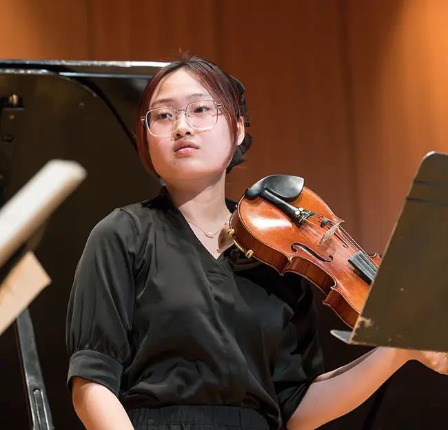 violinist holds violin and is listening.