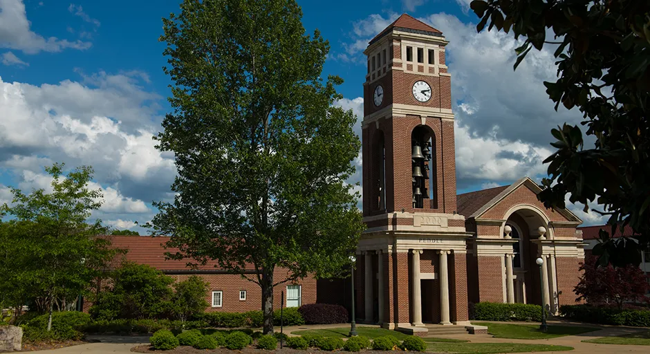 Brick exterior of chapel and tall bell tower with clock.