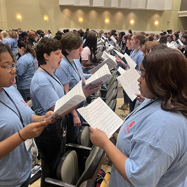 Group of people singing and holding sheet music