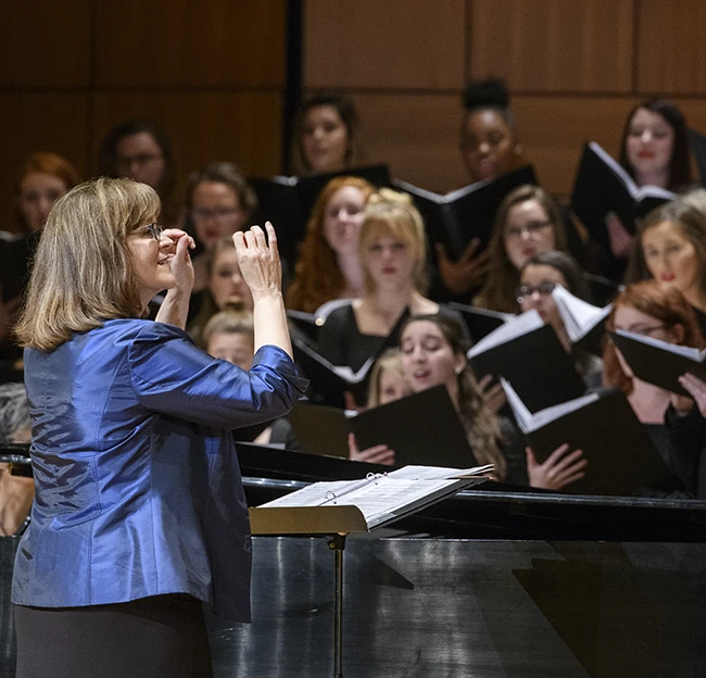 Elizabeth Hearn conducts the women's glee choir during a concert