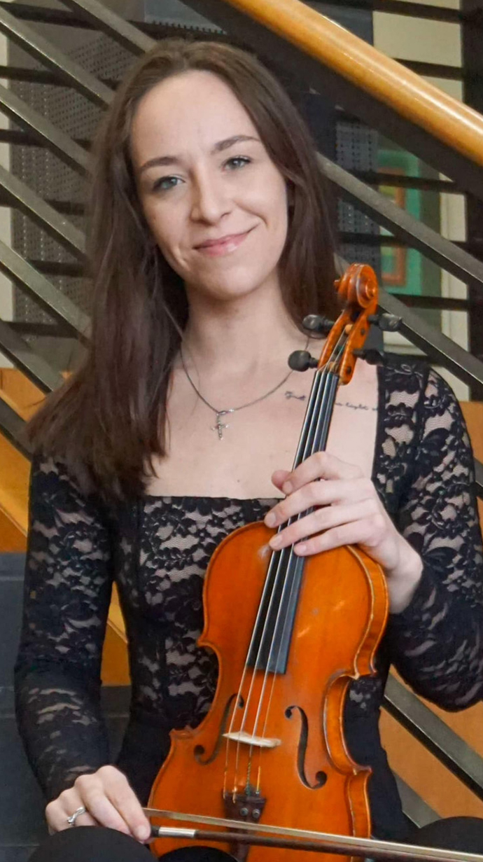 A young woman holds a violin.