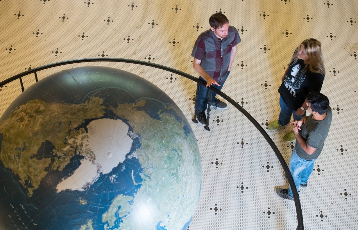 image of faculty and students standing by the globe in the lobby of Bryant