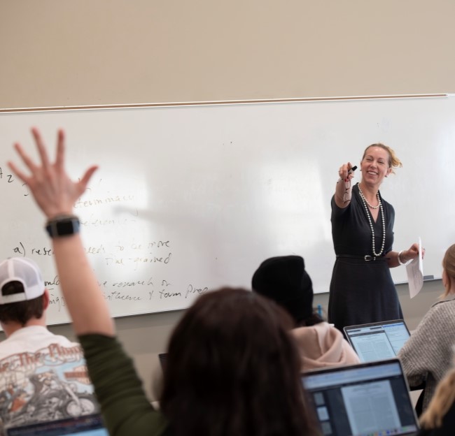 professor standing in front of class calling on a student who has raised her hand