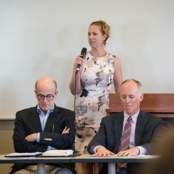 image of faculty member talking with business leaders seated at a table in front of her