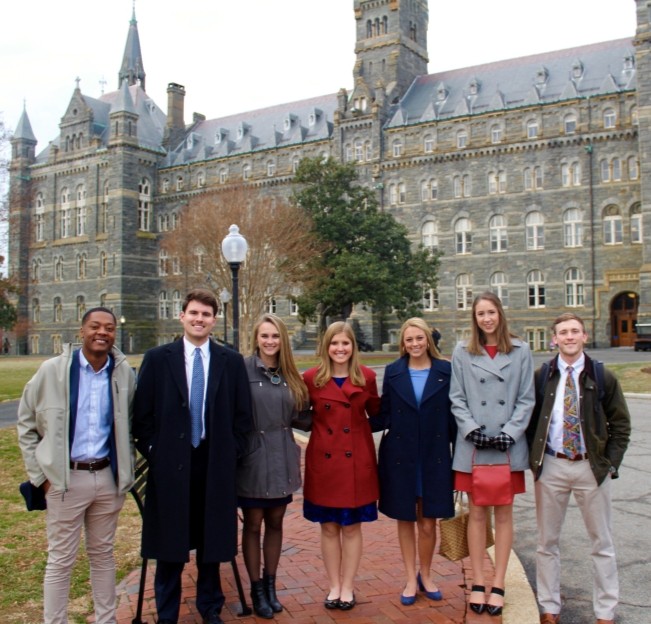 group of students standing outside in front of a large building