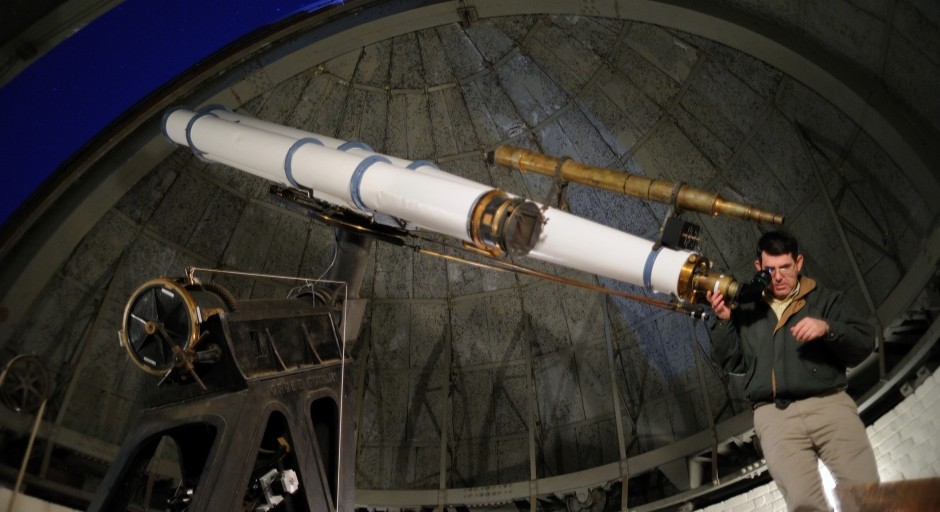 image of a man standing next to the telescope inside a dome