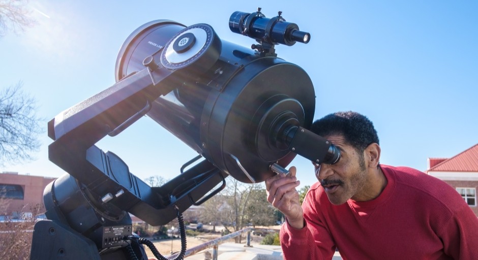 photo of a man looking through a solar telescope