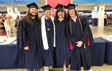 group of students standing together at commencement in graduation robes
