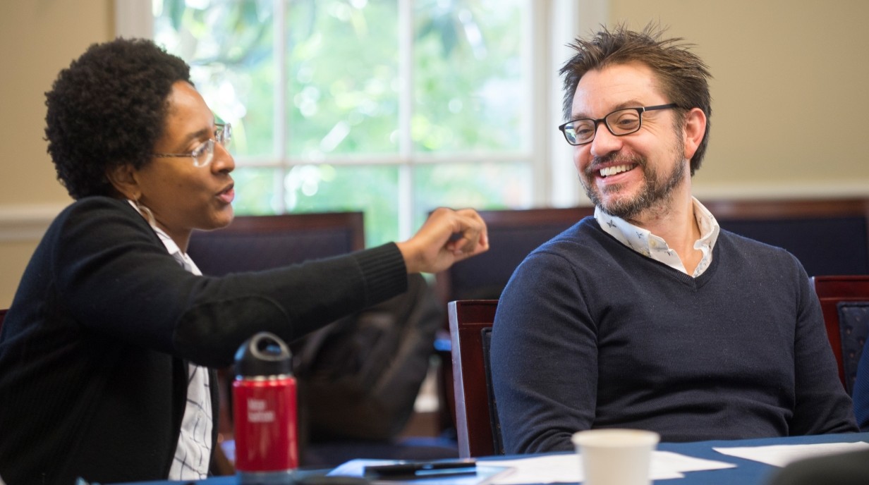 image of two faculty seated at a table and smiling to each other