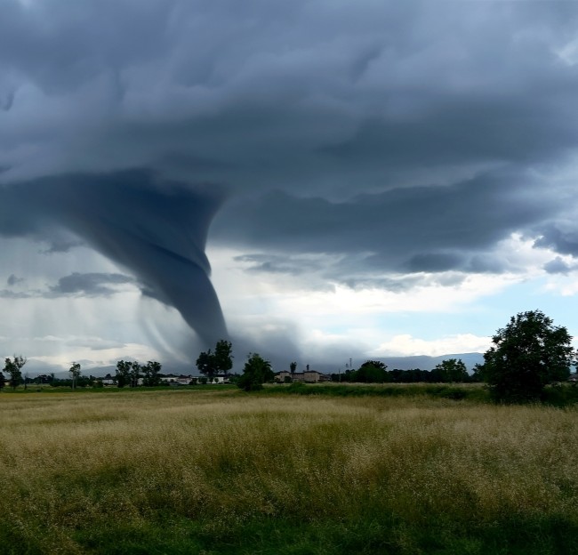 image of a tornado moving across the landscape with house and fields