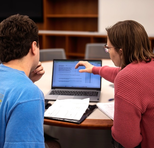 faculty member and student seated together looking at a computer screen