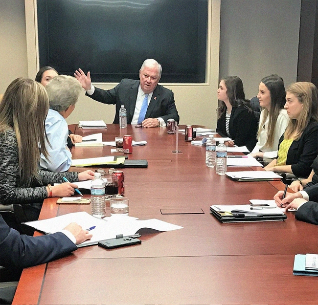 Haley Barbour gesturing and talking while seats around a table with students