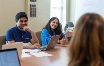 image of students talking and smiling around a conference table