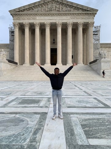 image of student standing in front of the Supreme Court building