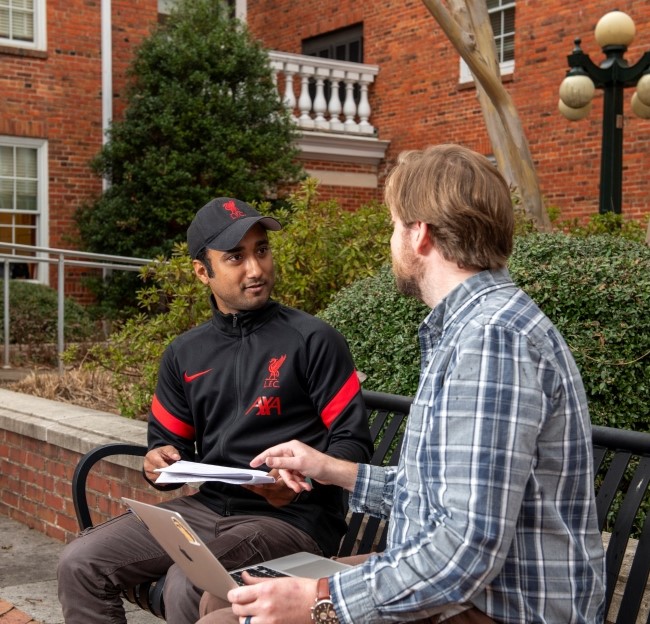 faculty member and graduate student sitting on a bench and talking