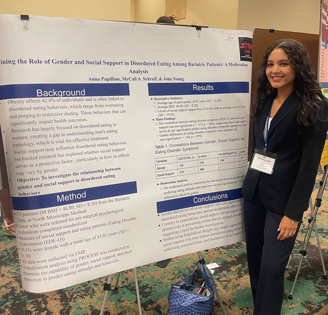 female student standing in front of poster presentation