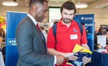 a businessman talking with a student at a career fair