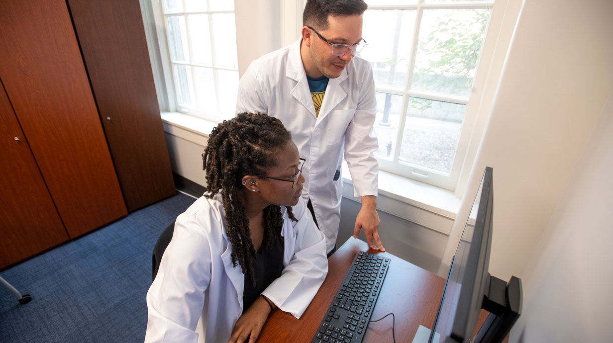 two people lab coats working on a computer