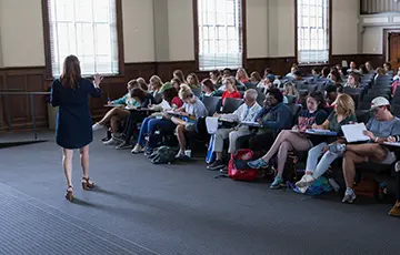 Professor standing in front of lecture hall filled with students