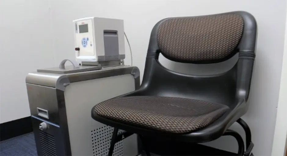 Chair with equipment (large metal box with smaller white box on top of it)next to it.