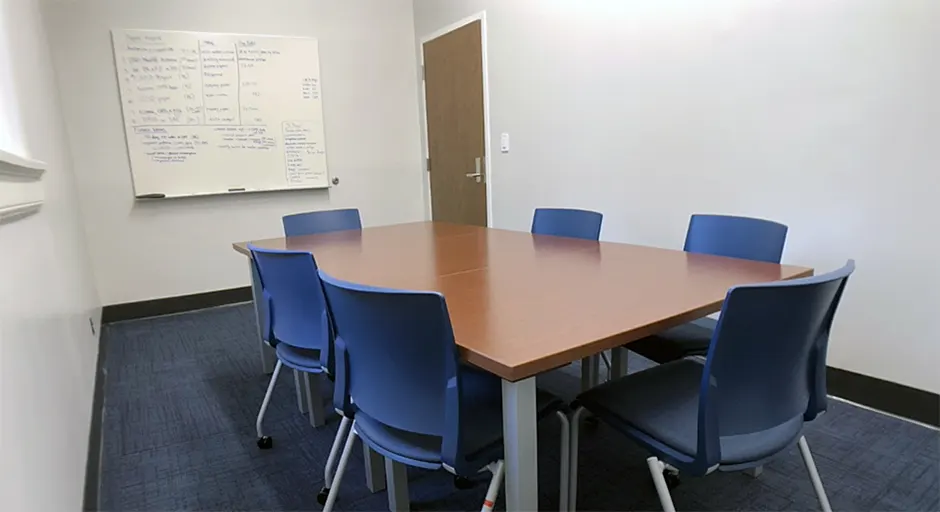 Small room with blue carpet; large whiteboard; and table and chairs