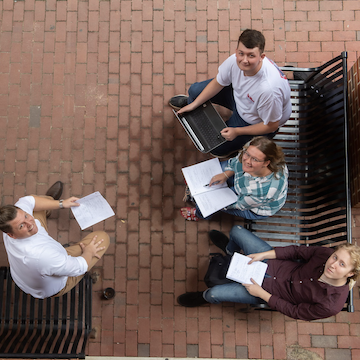 students converse on brick patio