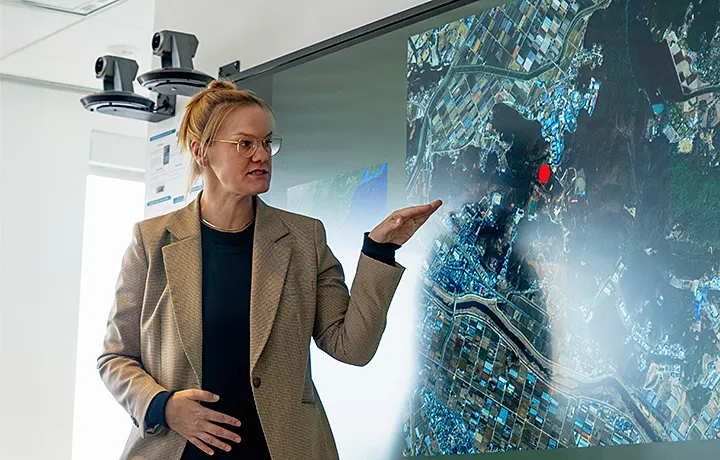 professor standing in front of a large map gesturing with hand