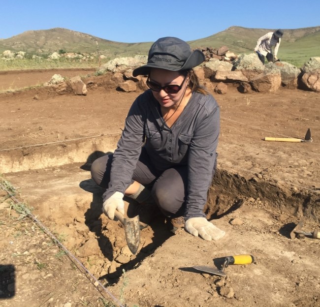 photo of Christine Lee sitting at an archaeological site working in a hole