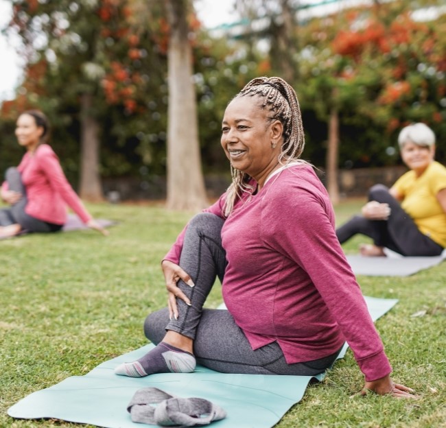 image of a few older women doing yoga on a lawn