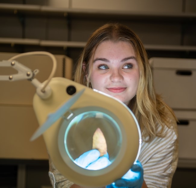 image of a student holding an arrow head under a circle light