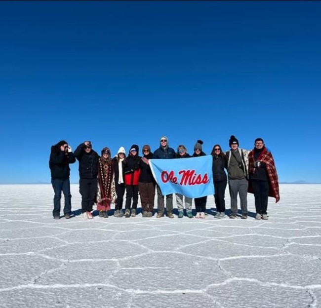 group of students standing on salt plain holding a banner with Ole Miss