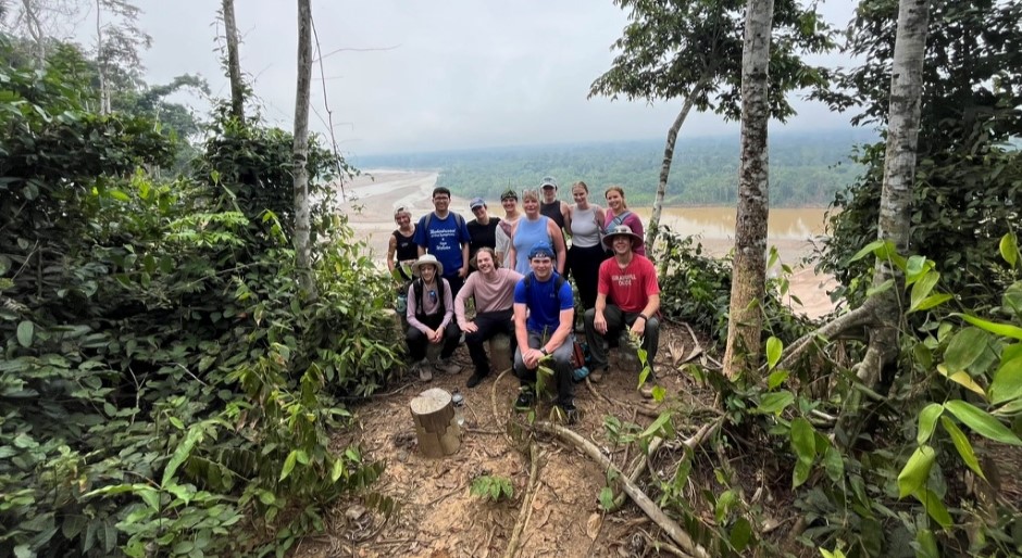 students taking a group photo with the rainforest in the background