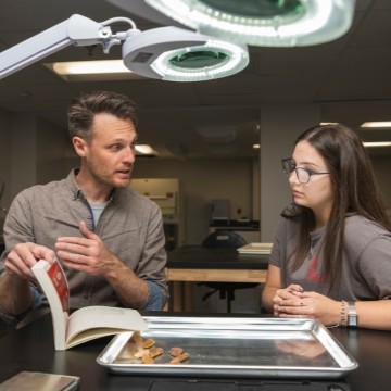 image of the faculty member and student working at table with artifacts