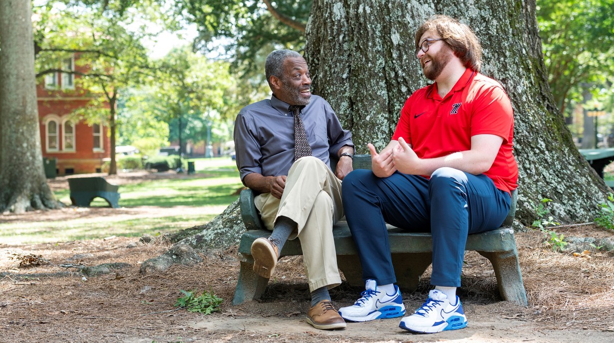 image of a faculty member and student seated on a bench and talking together
