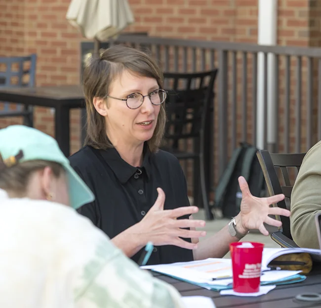image of Amy McDowell talking to students while seated at a table