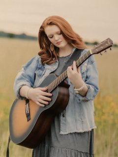 addie paige pratt holding a guitar outdoors