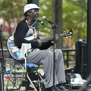 person seated playing guitar and harmonica